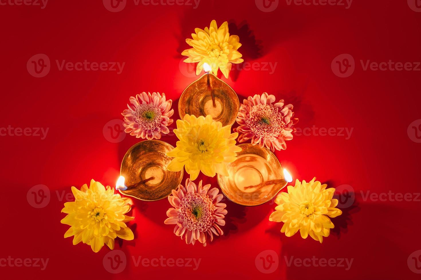 Happy Diwali. Traditional Hindu celebration. Diya oil lamps and flowers on red background. Religious holiday of light. photo