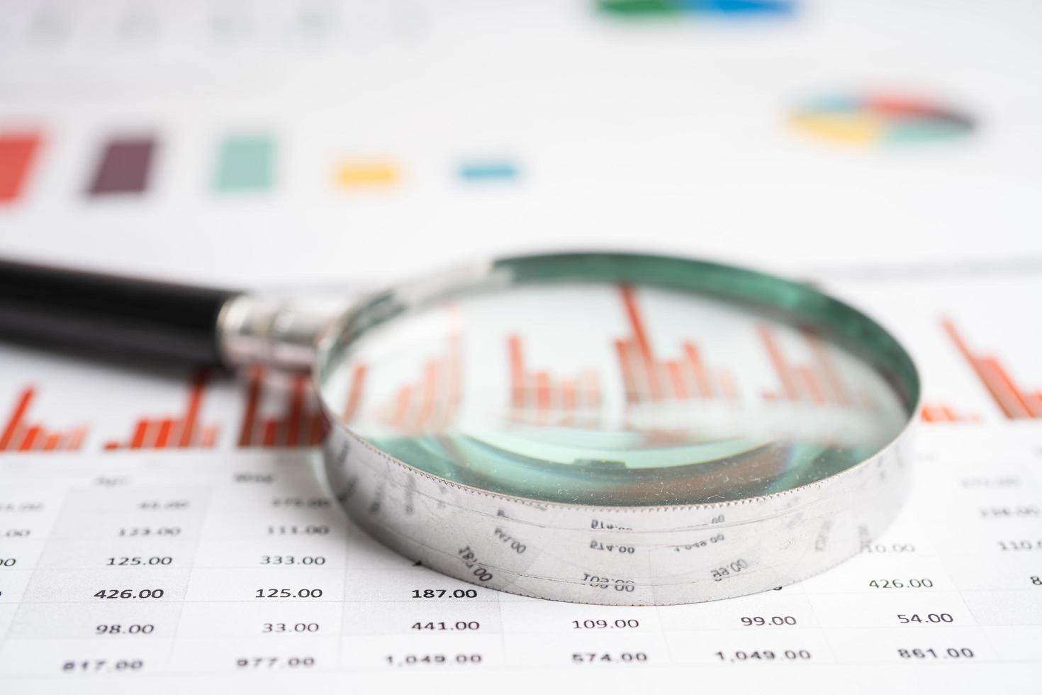 Magnifying glass on chart graph spreadsheet paper. Financial development, Banking Account, Statistics, economy, Stock exchange trading, Business office company meeting concept. photo