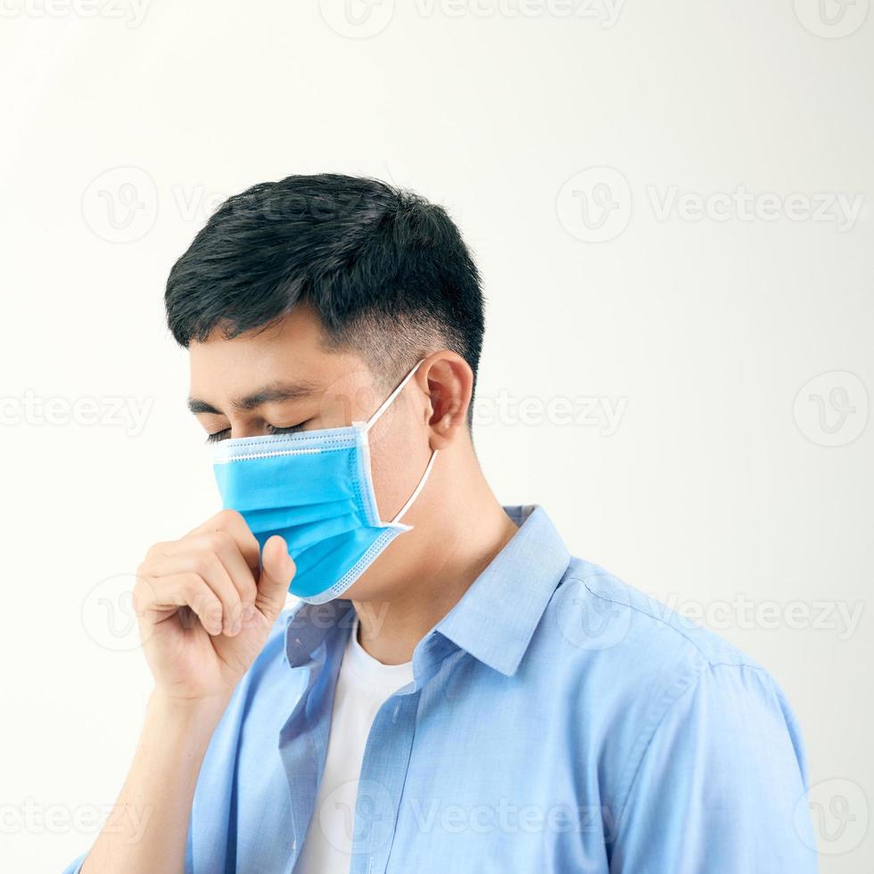 Asian man wearing surgical face mask coughing in subway station with crowded people walking pass. Wuhan coronavirus outbreak prevention photo