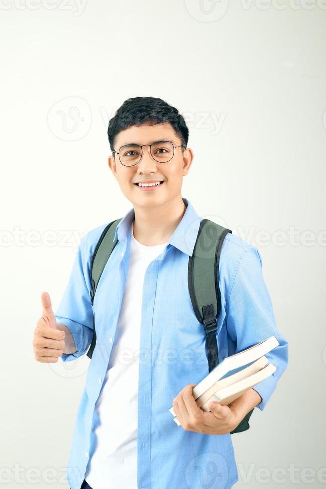 Portrait of a smiling male student with backpack showing thumbs up over white background photo
