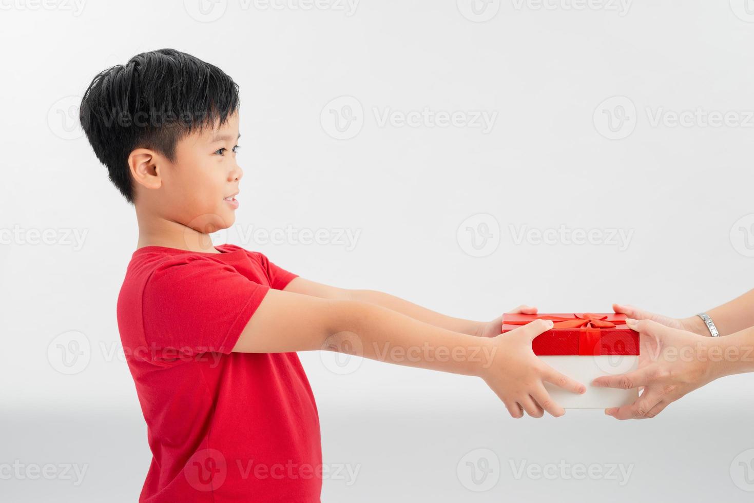 Take this present. Side view of cheerful generous good-natured little boy offering gift box and smiling happily photo