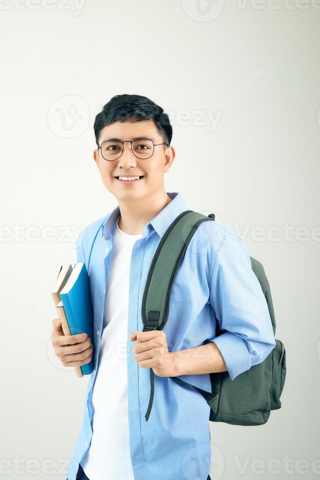 Guapo estudiante feliz sonriendo y una mochila y cuadernos sobre fondo blanco. foto