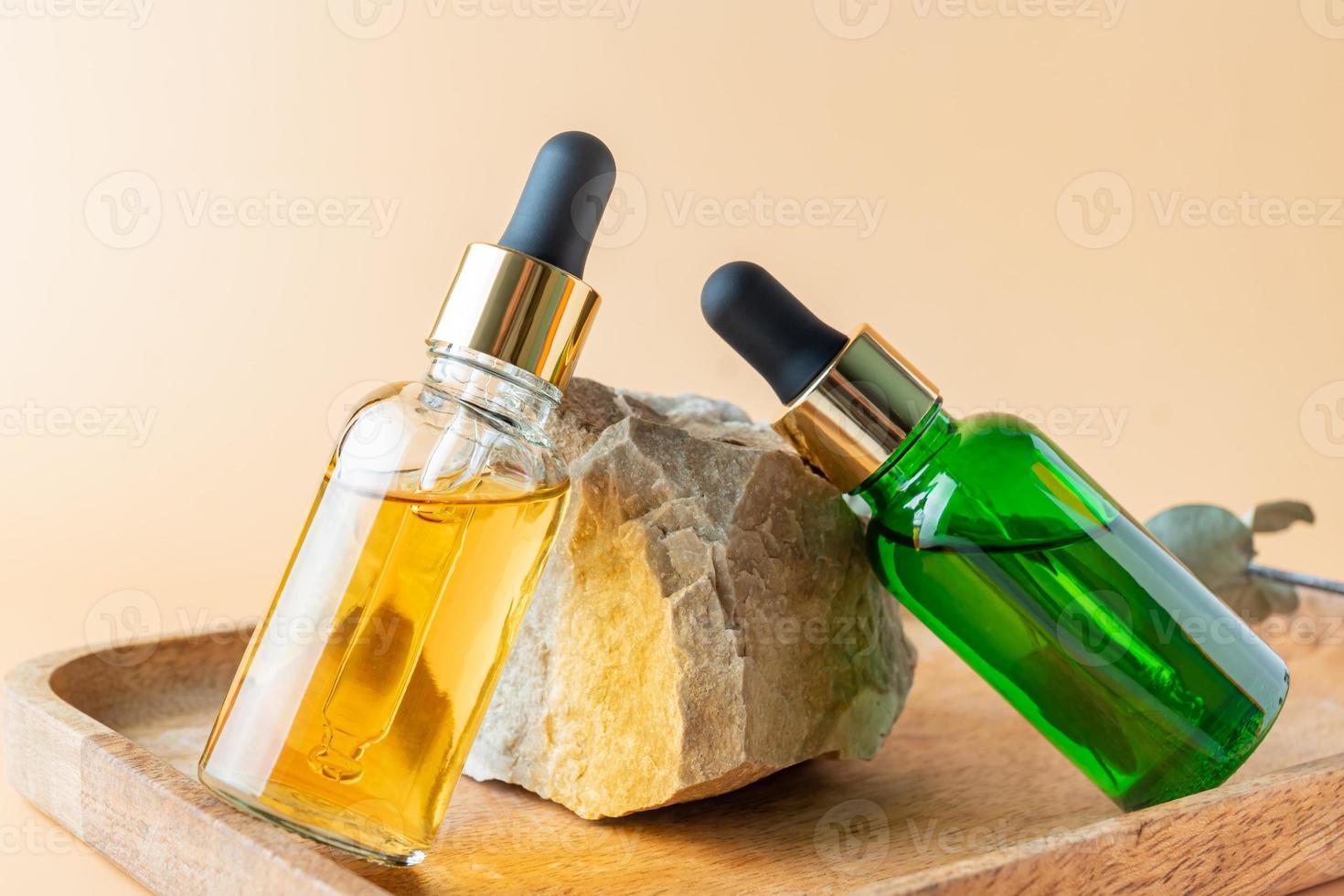 producto natural para el cuidado de la piel en botellas de vidrio con cuentagotas. suero para la piel del rostro de la mujer. cosmético mineral a base de hierbas, aceite corporal vitamínico en soporte de roca. presentación de someticos orgánicos foto