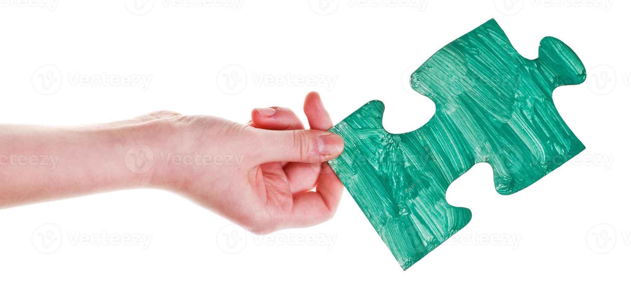 female hand with painted green puzzle piece photo