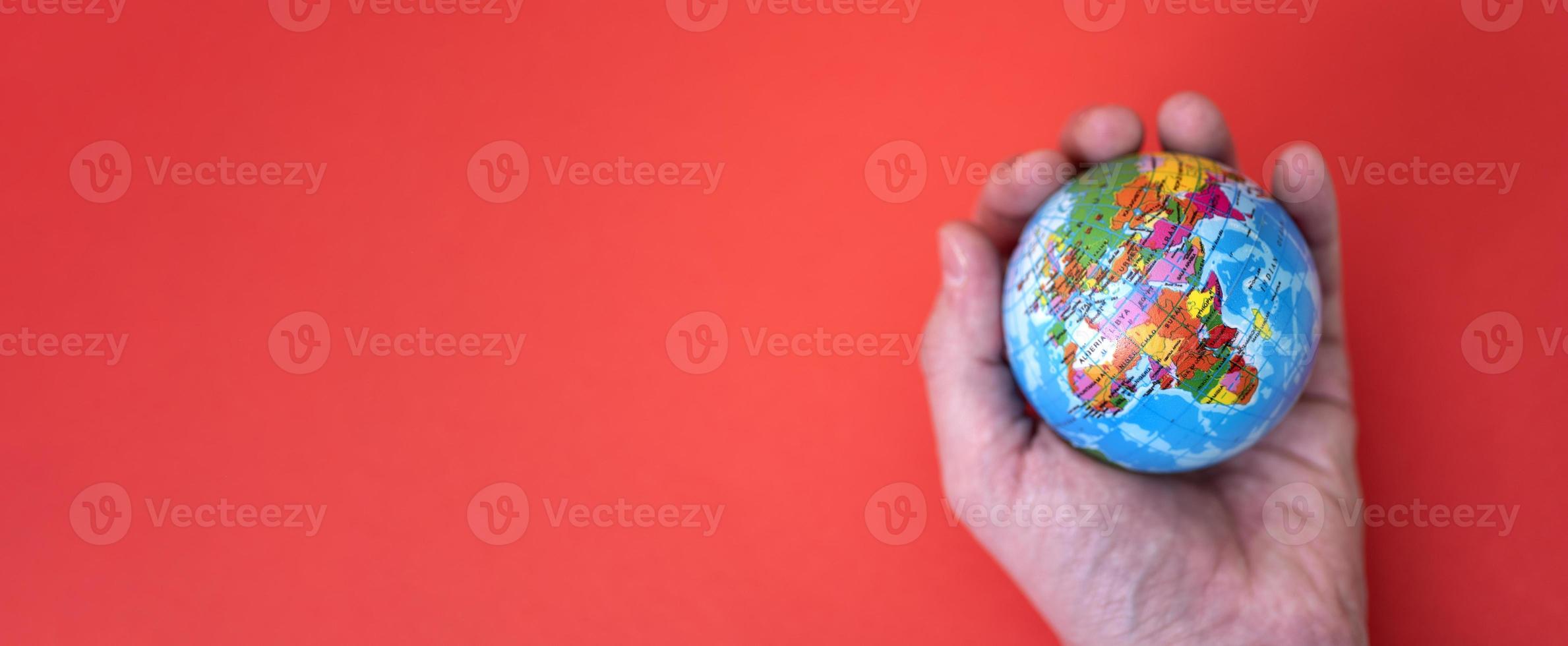 Globe in hand on red and paper background with space for text. photo