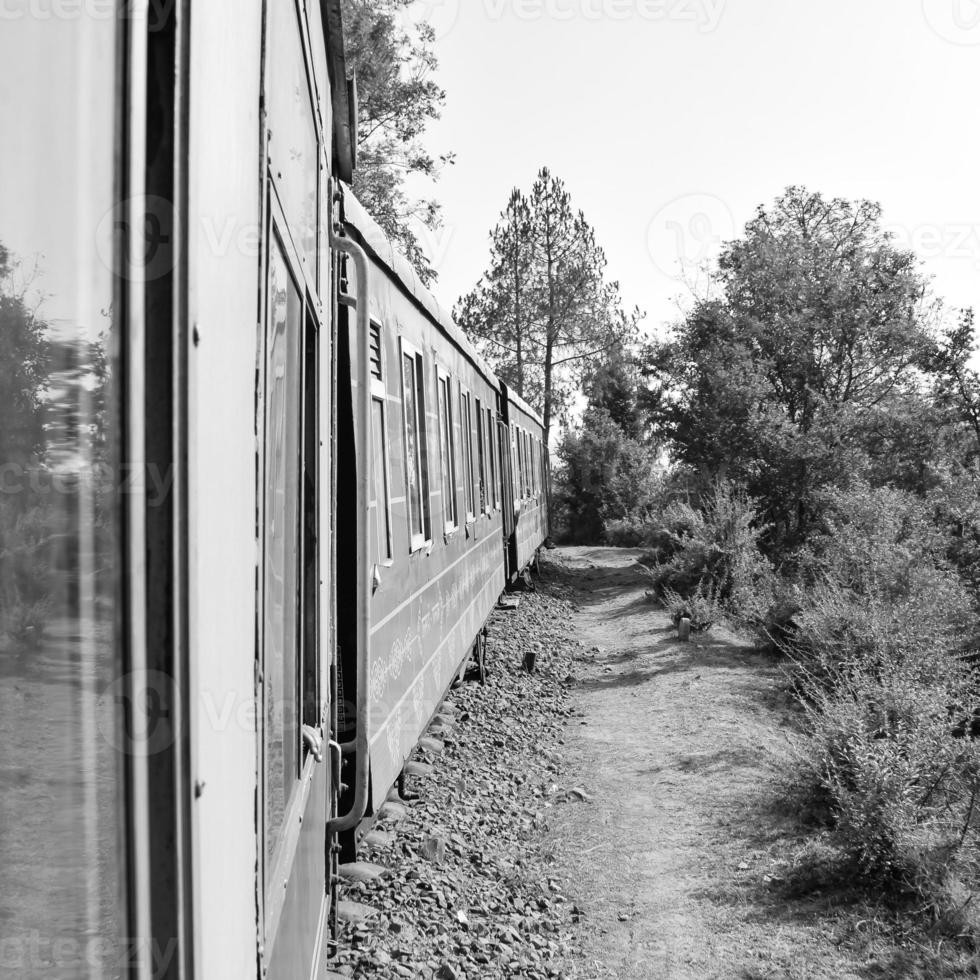 Toy Train moving on mountain slope, beautiful view, one side mountain, one side valley moving on railway to the hill, among green natural forest.Toy train from Kalka to Shimla in India-Black and White photo
