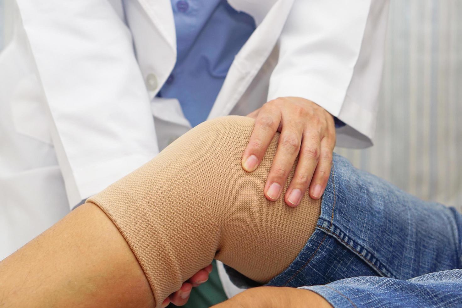 Doctor examining the knee of a patient with a bandage. Concept of Health check, health care and medical. photo