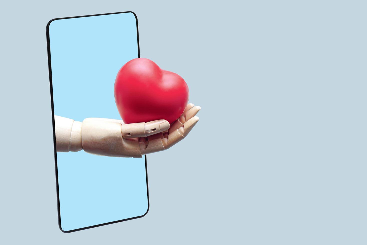 la mano del robot da un corazón rojo desde un teléfono inteligente negro, conectado a la comunicación tecnológica en línea. tecnología médica y concepto futuro. foto