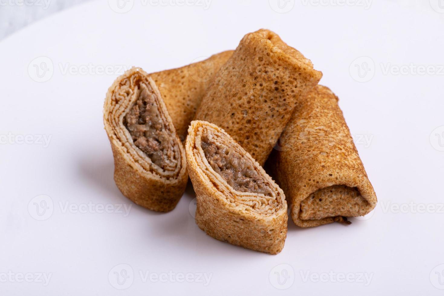 A closeup shot of stuffed pancakes with meat on a white background photo