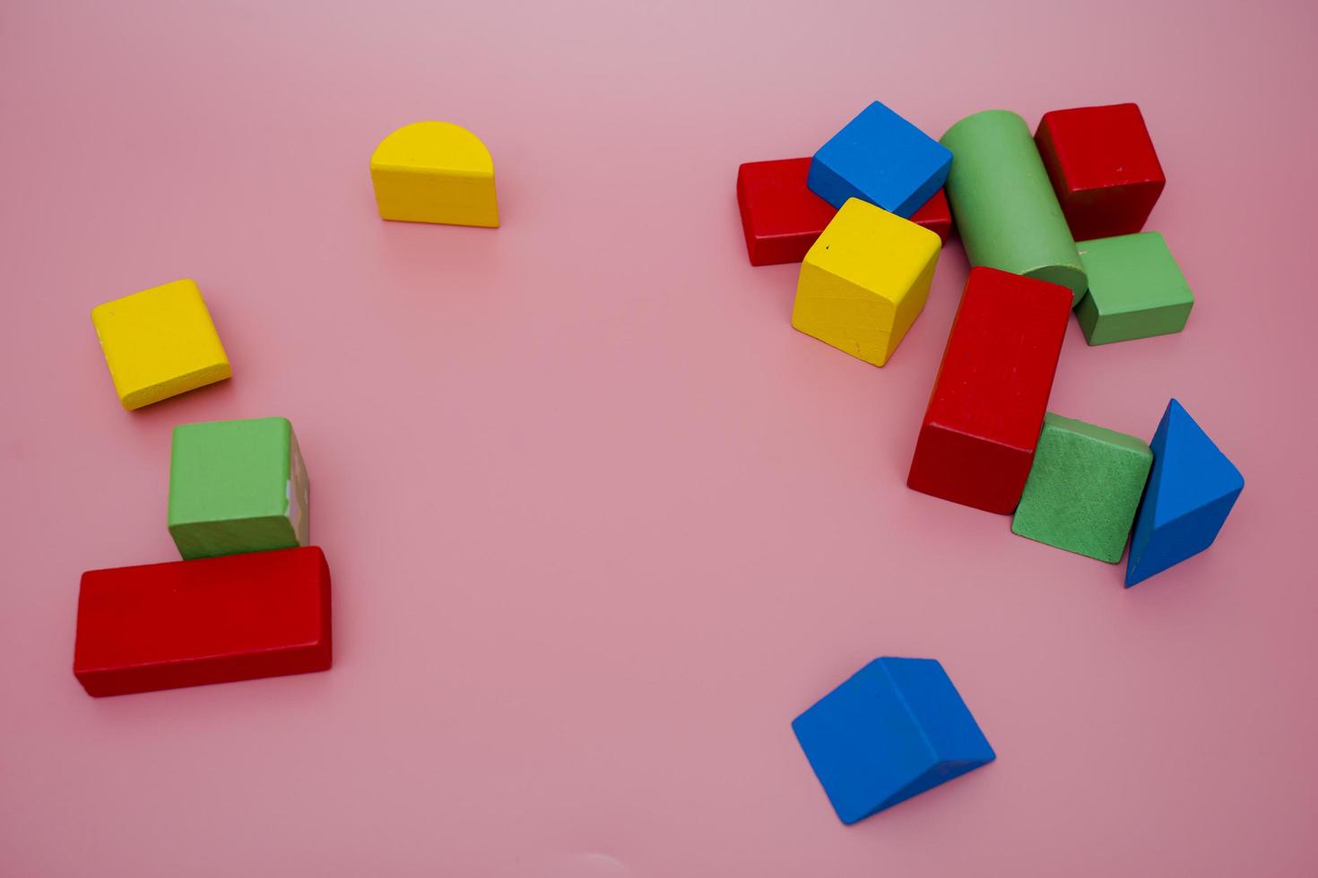 Colorful wooden blocks on pink background. Creativity toys. Children's building blocks. Geometric shapes - cube, triangular prism, cylinder. The concept of logical thinking. photo