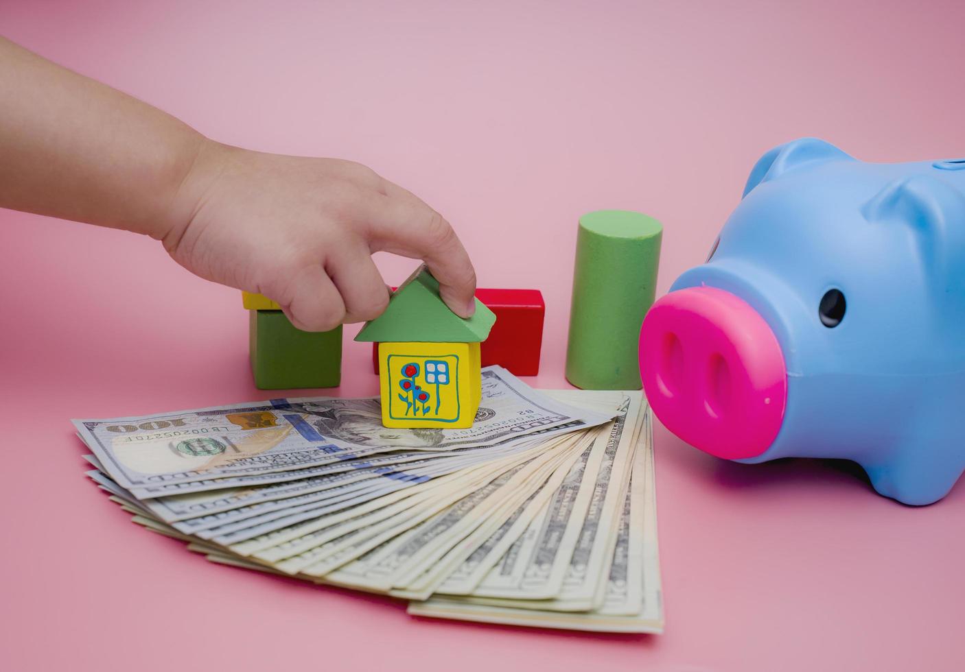 Hand of the kids take a wood block with small  house models on top of block.Concept of saving money for future , investment property and saving money to buy a house. On blur background. photo