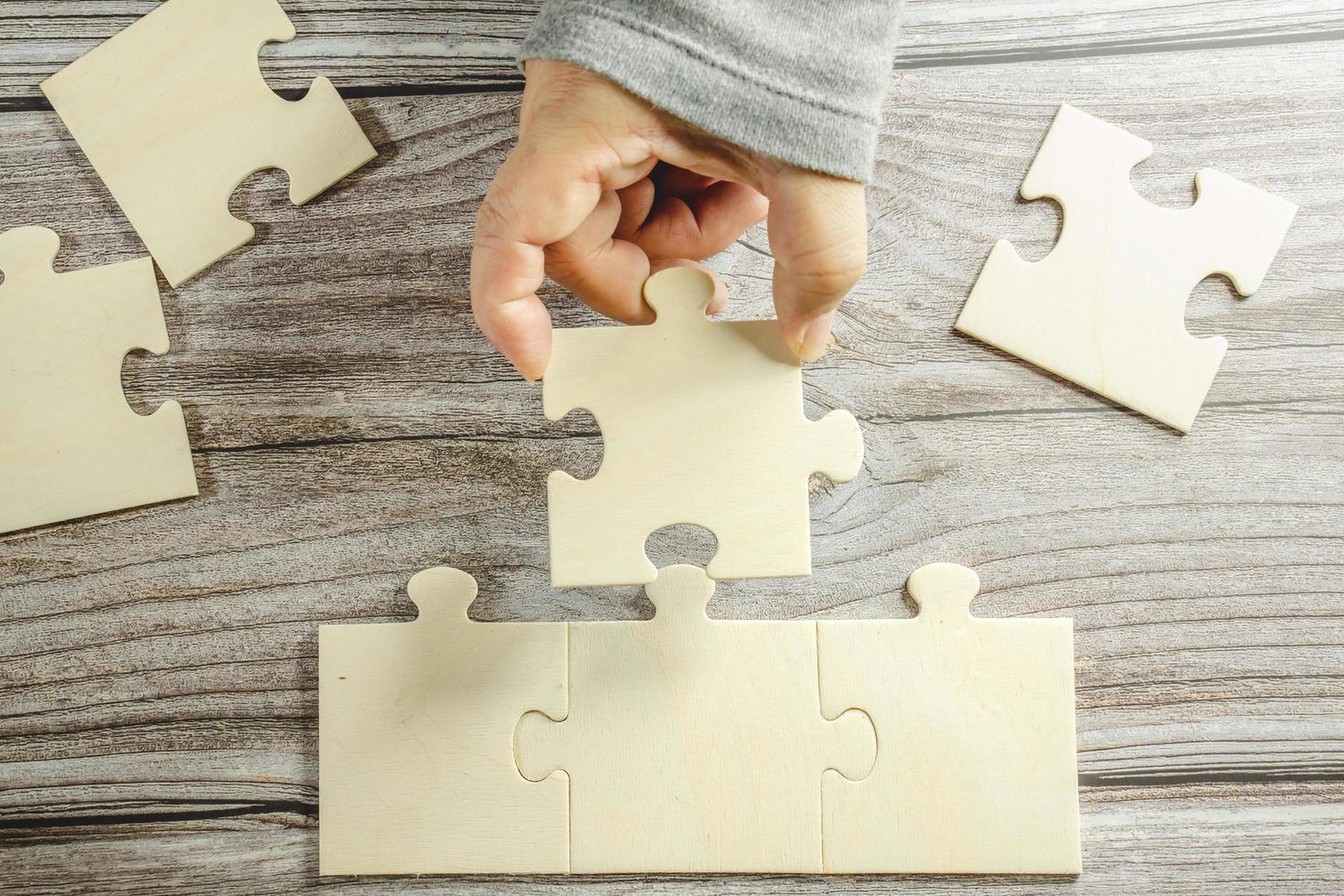 White jigsaw puzzle connecting together. Team business success partnership or teamwork concept. A group of business people assembling jigsaw puzzle. Business solutions, success and strategy concept. photo