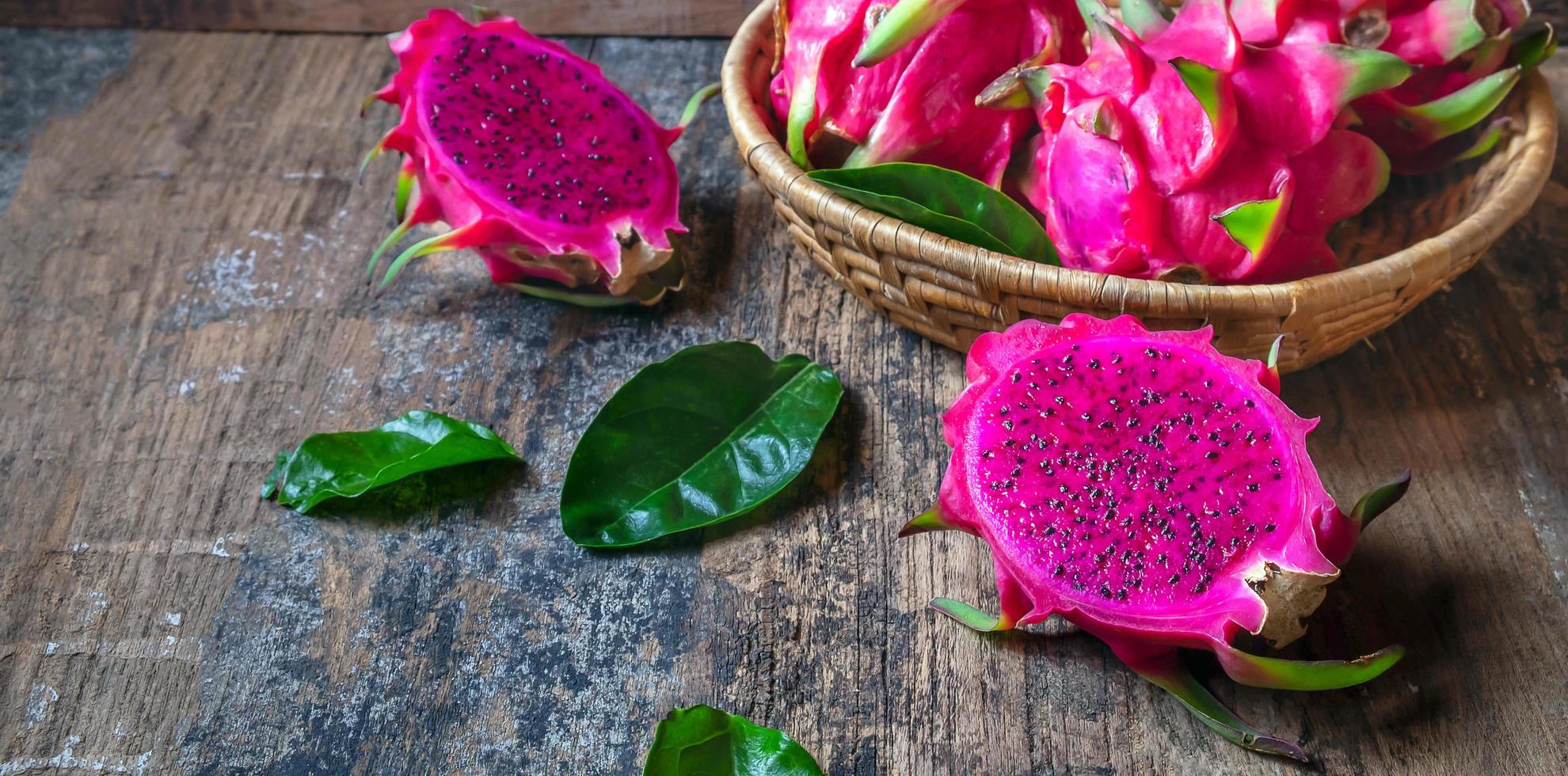 la vista superior de la fruta del dragón rojo en rodajas medias del género hylocereus pertenece a la familia cactaceae, que es la misma familia que el cactus sobre fondo de madera foto