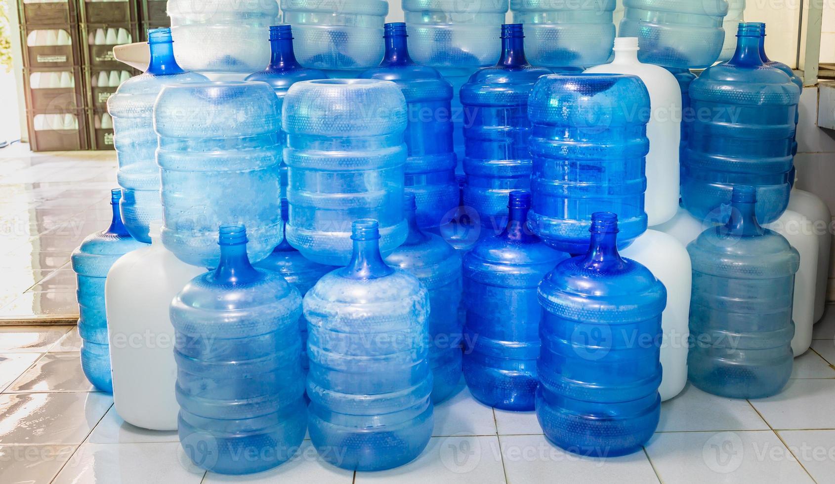 Blue plastic bottles or blue gallons of drinking water are stacked in the drinking water factory to cycle the drinking water.water factory  business concept photo
