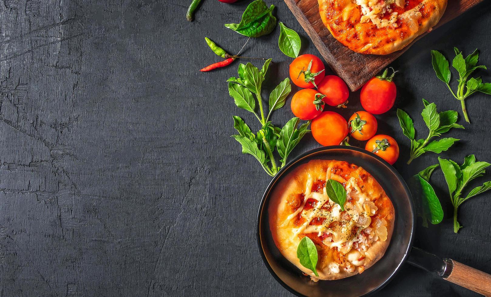 Top view of home made pizza, vegetables, ingredients on a Black wooden  background. Pizza is cooking in the pan. Pizza photo