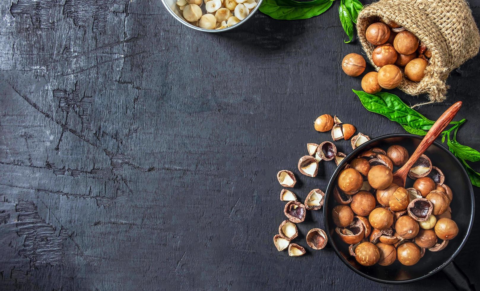 Organic dry Macadamia nut in a brown sack on black wooden background photo