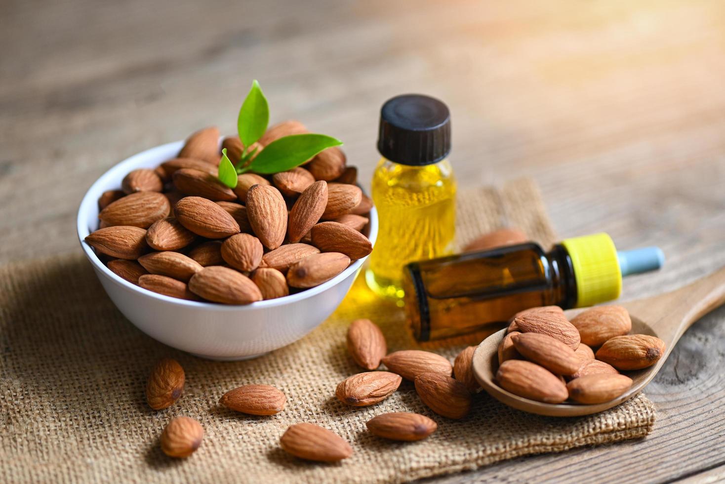 Almond oil and Almonds nuts on bowl, Delicious sweet almonds oil in glass bottle, roasted almond nut for healthy food and snack organic vegetable oils for cooking or spa concept photo