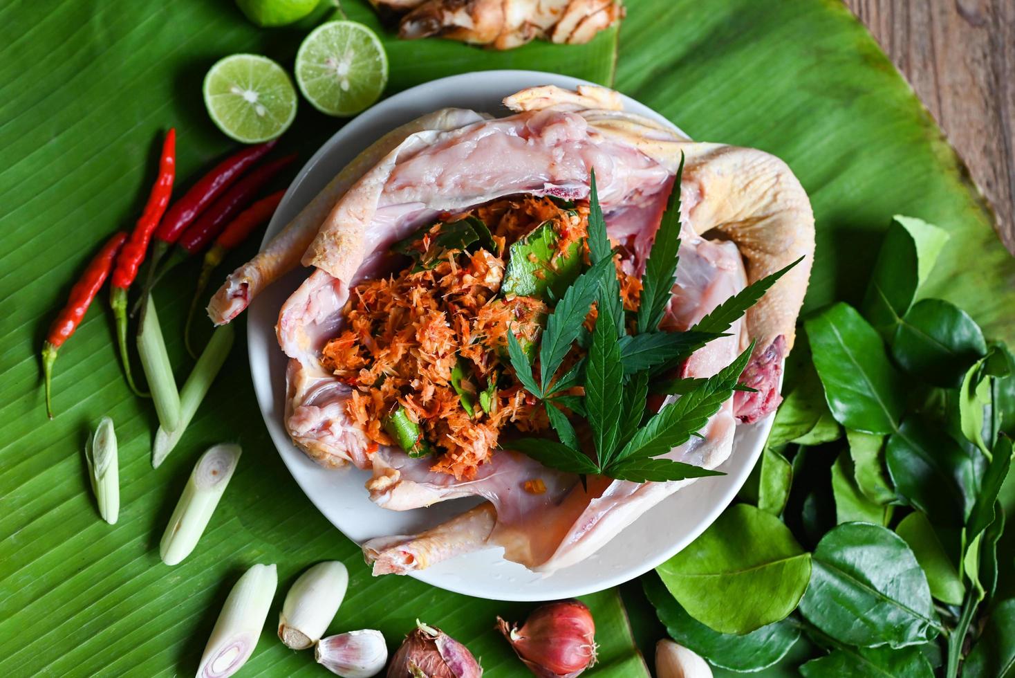 Cannabis food for cooking with fresh chicken cannabis leaf marijuana vegetables herbs and spices ingredients on banana leaf background, raw chicken hemp leaf plant THC CBD herbs - Thai food photo