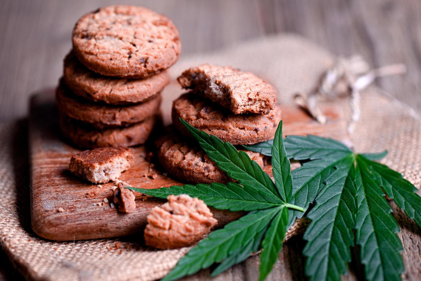 delicious sweet dessert cookie with hemp leaf plant THC CBD herbs food snack and medical, Cannabis food cookies with cake chocolate cannabis leaf marijuana herb on wooden background photo