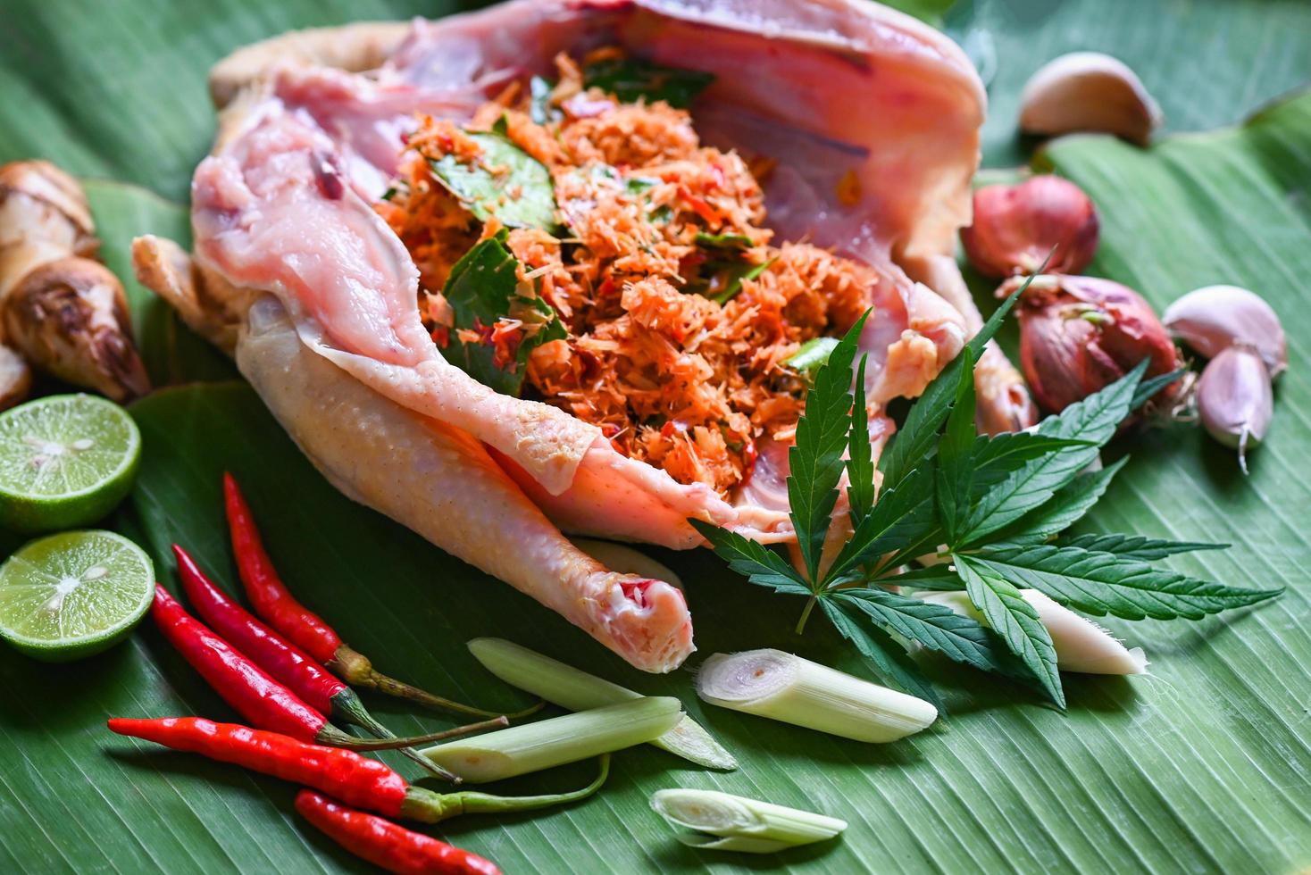 comida de cannabis para cocinar con pollo fresco hoja de cannabis marihuana verduras hierbas y especias ingredientes sobre fondo de hoja de plátano, pollo crudo hoja de cáñamo planta thc cbd hierbas - comida tailandesa foto