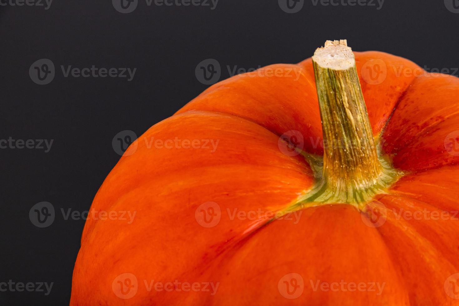 Orange pumpkin with a stem, close-up on a black background. Autumn background. Copy space. photo