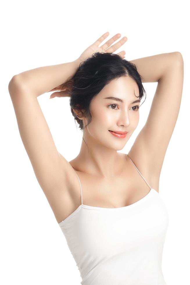 Asian woman with a beautiful face and Perfect clean fresh skin. Cute female model rising arm show her armpit on white isolated background. Facial treatment, Cosmetology, beauty Concept. photo