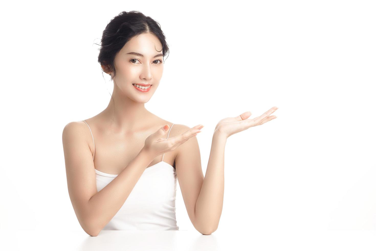 Asian woman with a beautiful face and Perfect clean fresh skin. Cute female model showing concept or idea on copy space on white isolated background. Facial treatment, Cosmetology, beauty Concept. photo