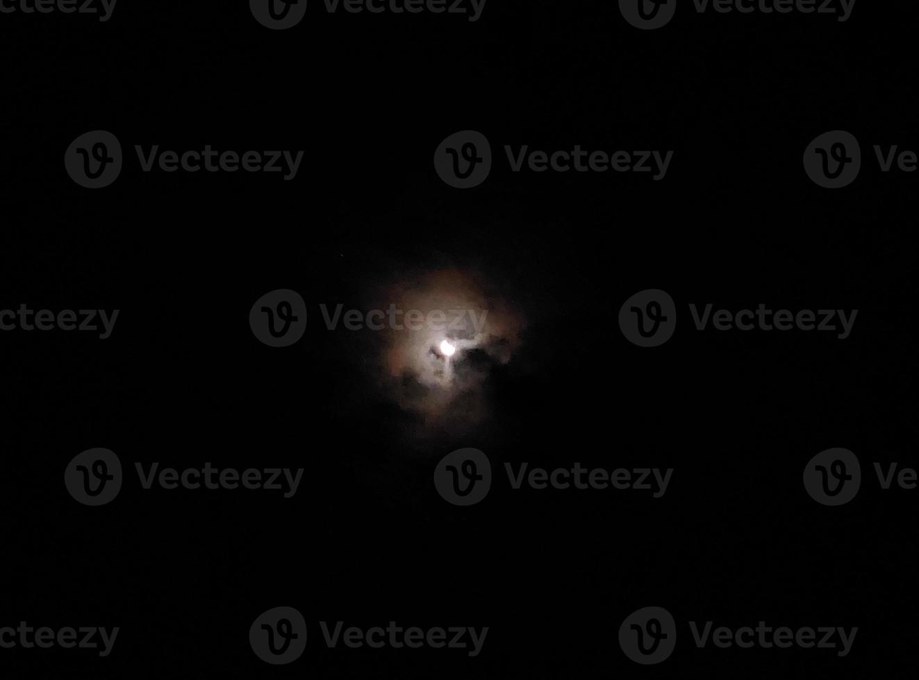 Moon in the clouds in the night sky photo