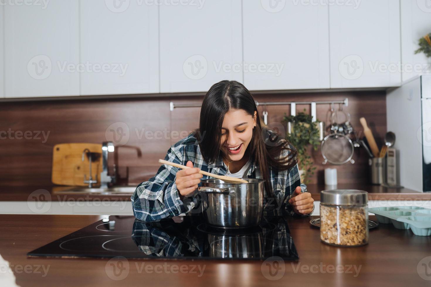 Young happy girl cooking on electric stove photo