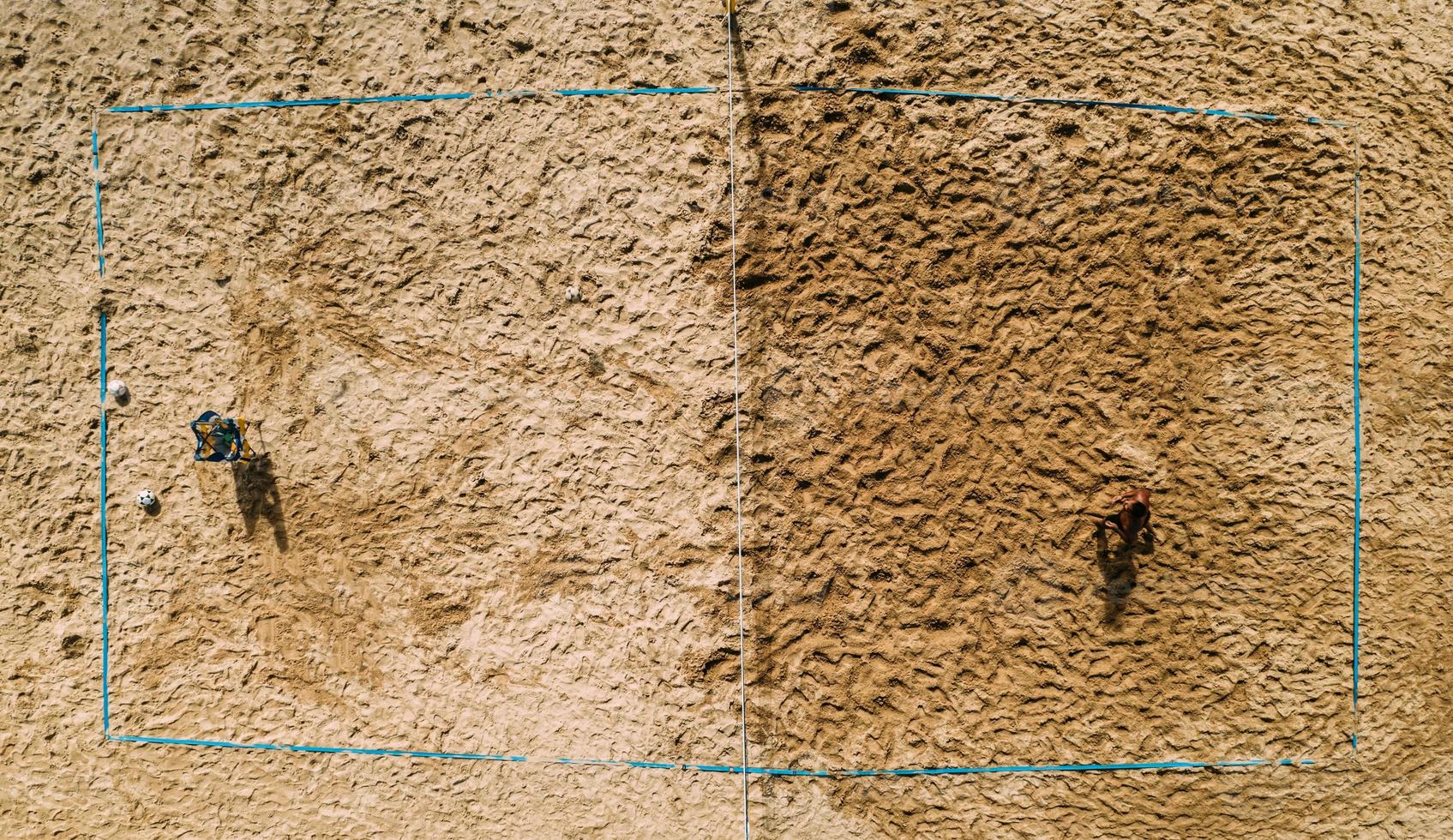 Top down drone view of unidentifiable shirtlesss male at a beach volleyball court photo