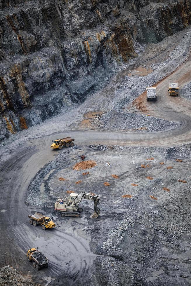 Work of trucks and the excavator in an open pit on gold mining photo