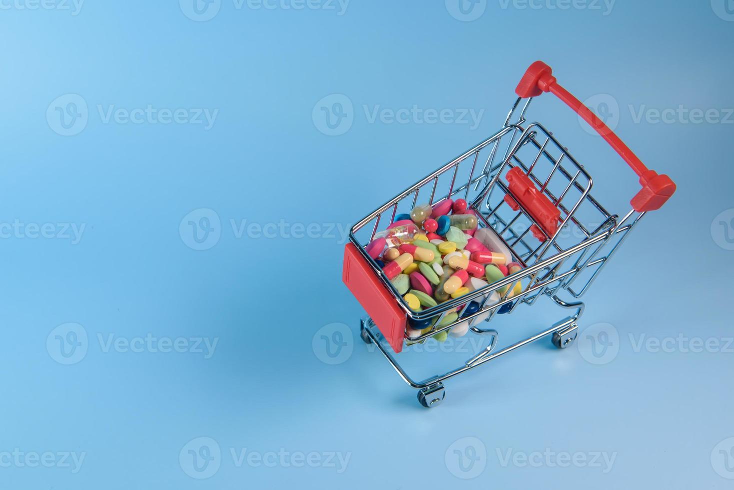 Buy medicine. Shopping basket with various medicinal, pills, tablets on blue background. Studio Photo