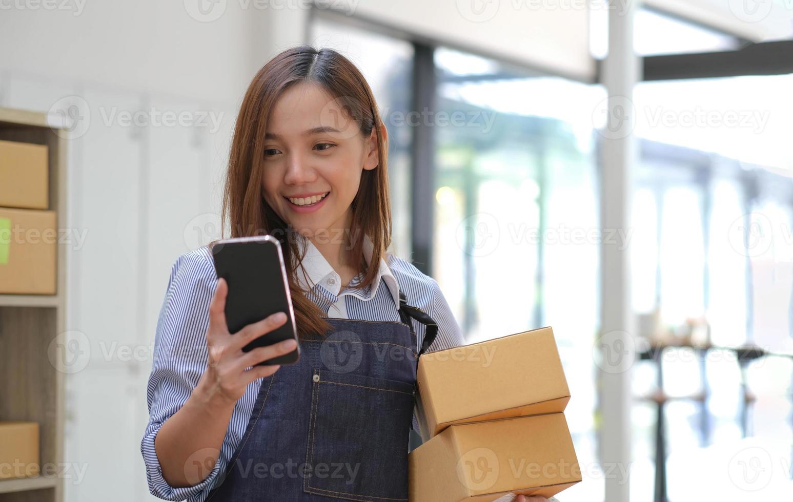 Startup small business entrepreneur SME, asian woman receive order on phone. Portrait young Asian small business owner home office, online sell marketing delivery, SME e-commerce telemarketing concept photo