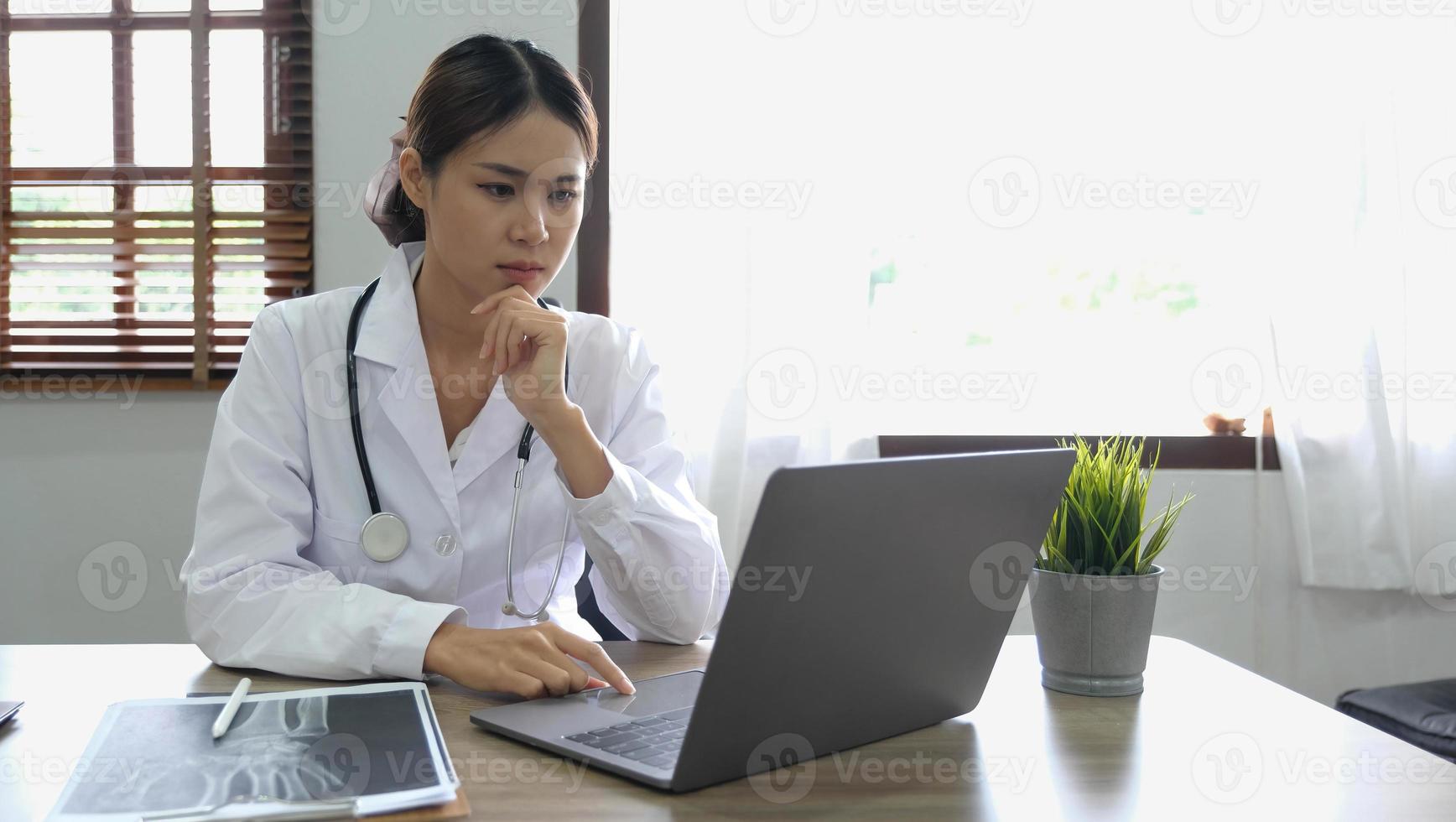 Portrait happy asian woman doctor, Telemedicine concept. Asian female doctor talking with patient using laptop online video webinar consultation while sitting in clinic office photo