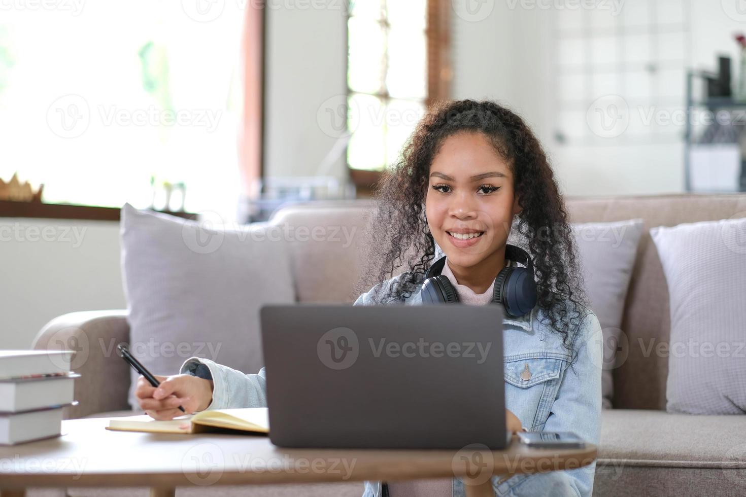 retrato de una estudiante feliz con piel oscura sonriendo a la cámara. alegre chica hipster afroamericana disfrutando del aprendizaje electrónico y la preparación para el trabajo del curso foto