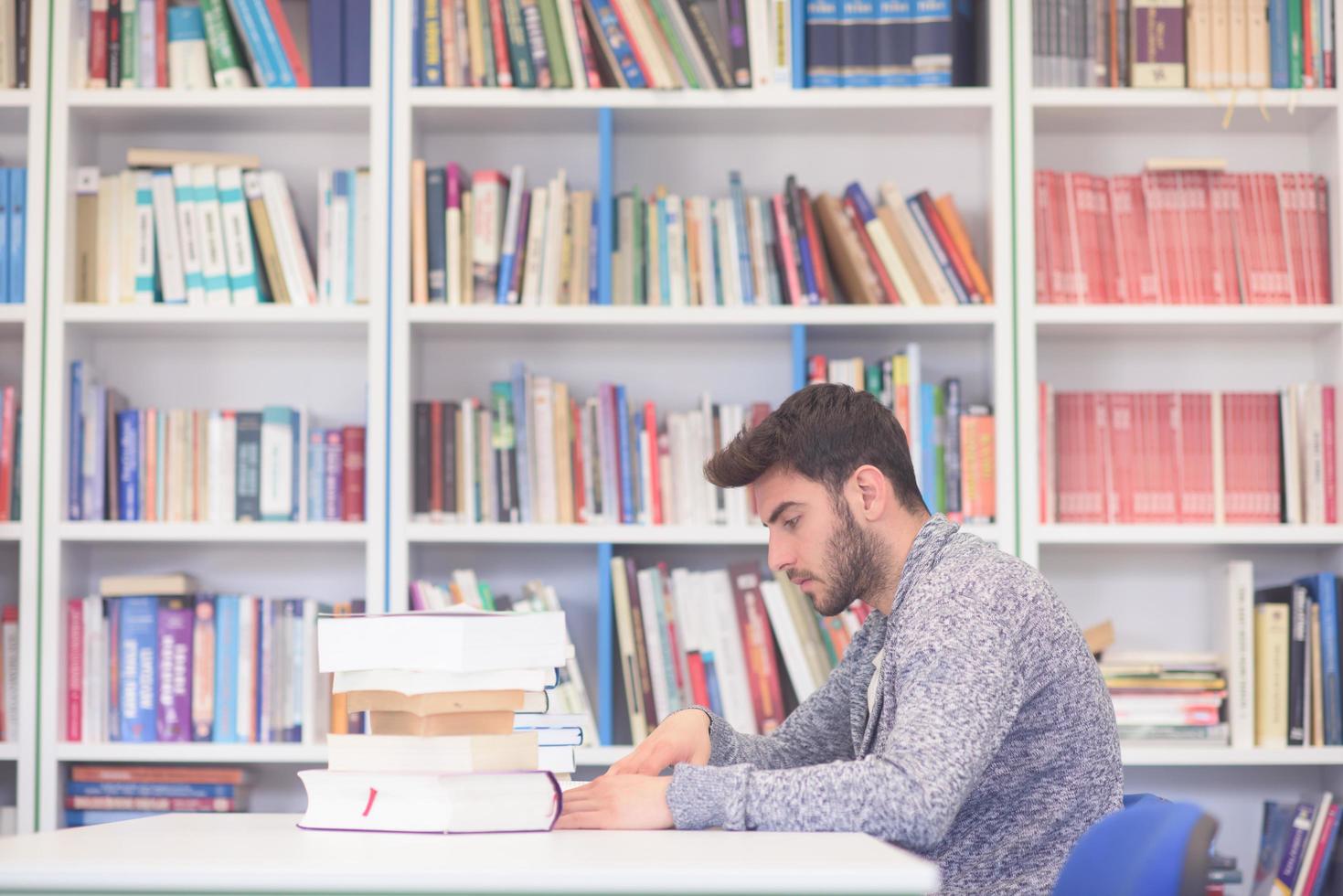 portrait of student while reading book  in school library photo