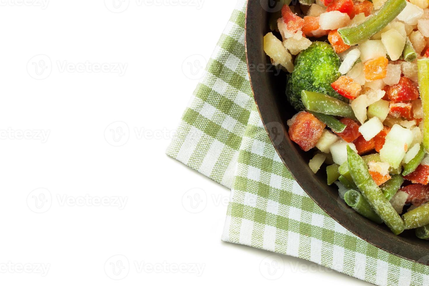 Mixture of frozen vegetables in black pan isolate on white background photo