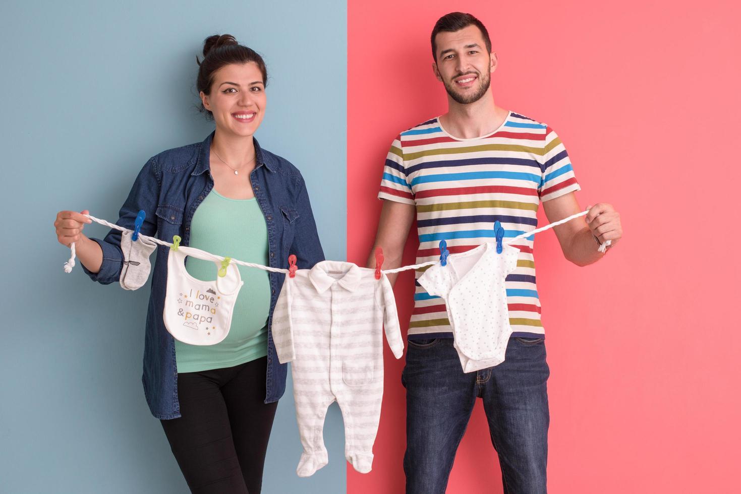 young couple holding baby bodysuits photo