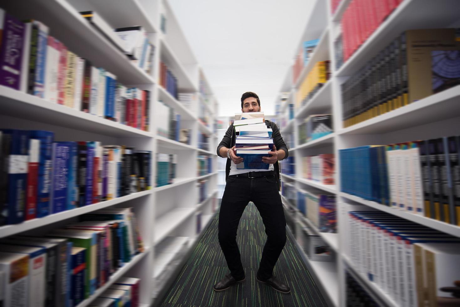 Student holding lot of books in school library photo