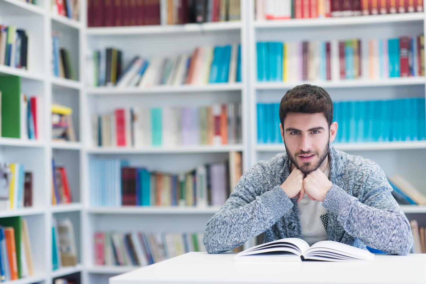 portrait of student while reading book  in school library photo