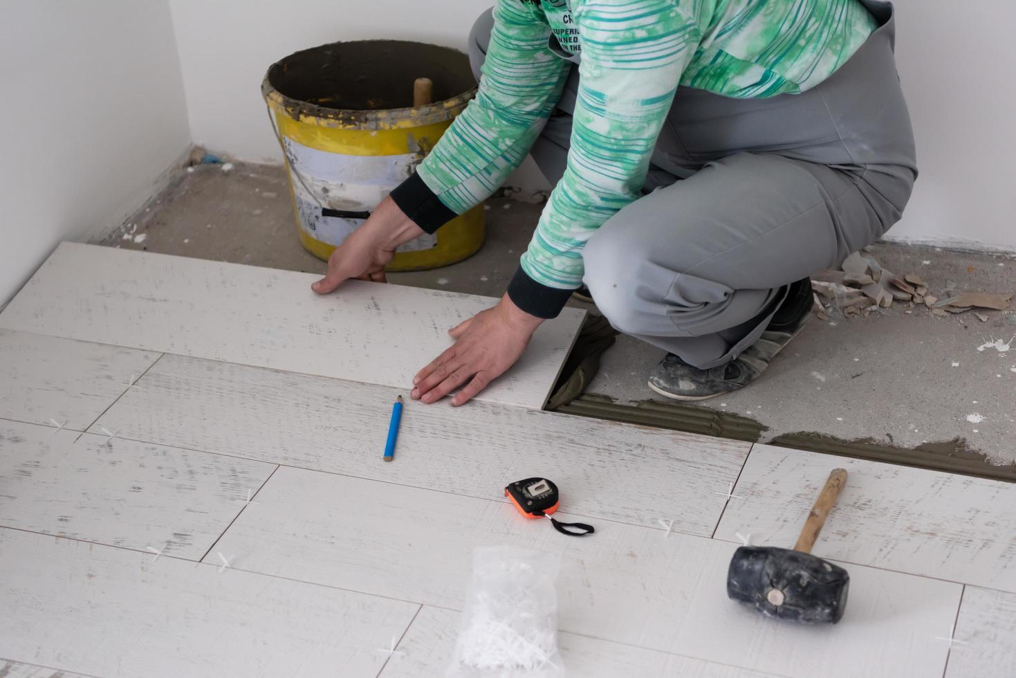 worker installing the ceramic wood effect tiles on the floor photo