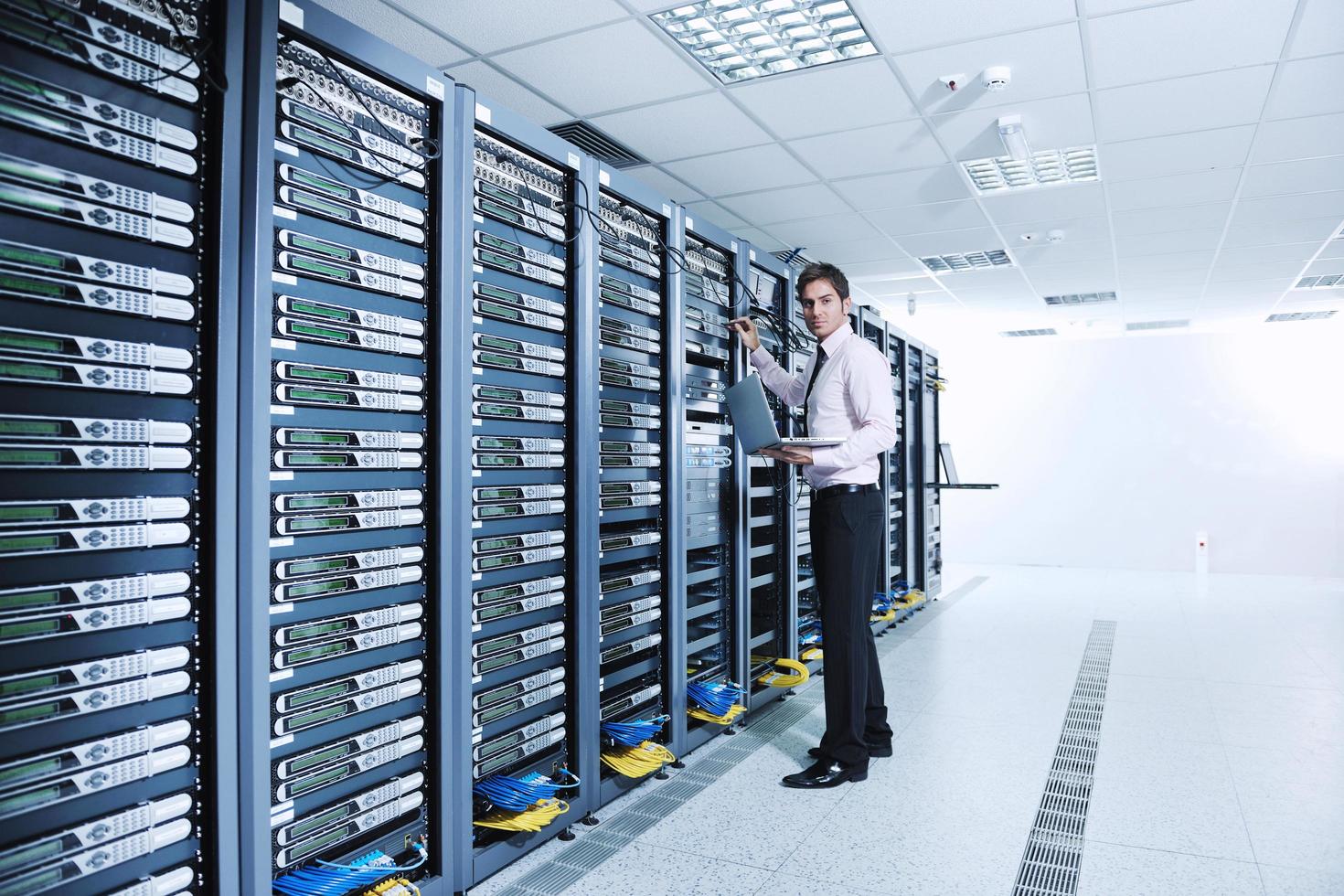 businessman with laptop in network server room photo