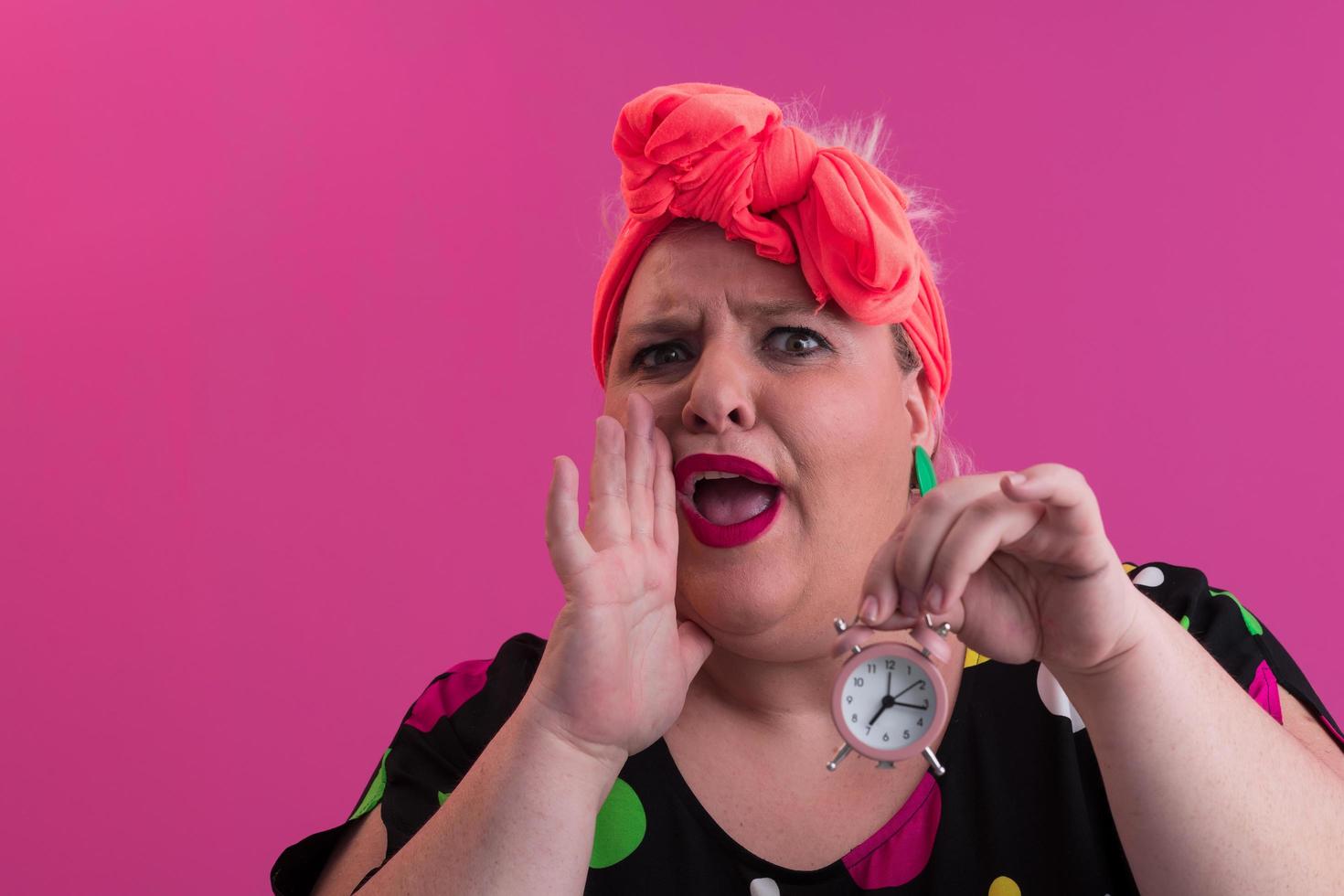 Portrait of plus size young lady smiling hands holds sand clock isolated on pink color background. photo