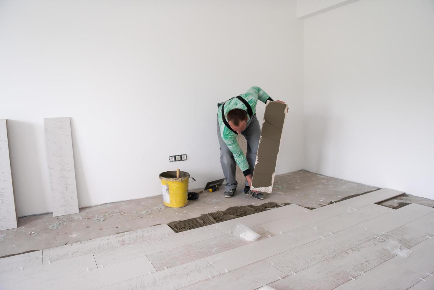 worker installing the ceramic wood effect tiles on the floor photo