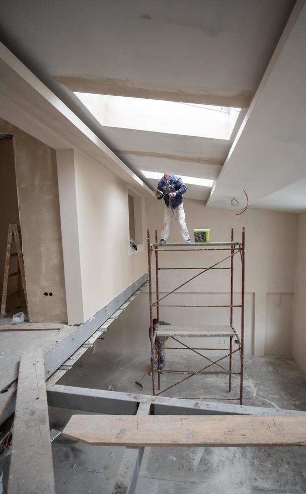 construction worker plastering on gypsum ceiling photo