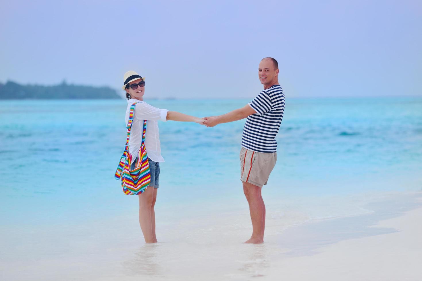 feliz pareja joven divertirse en la playa foto