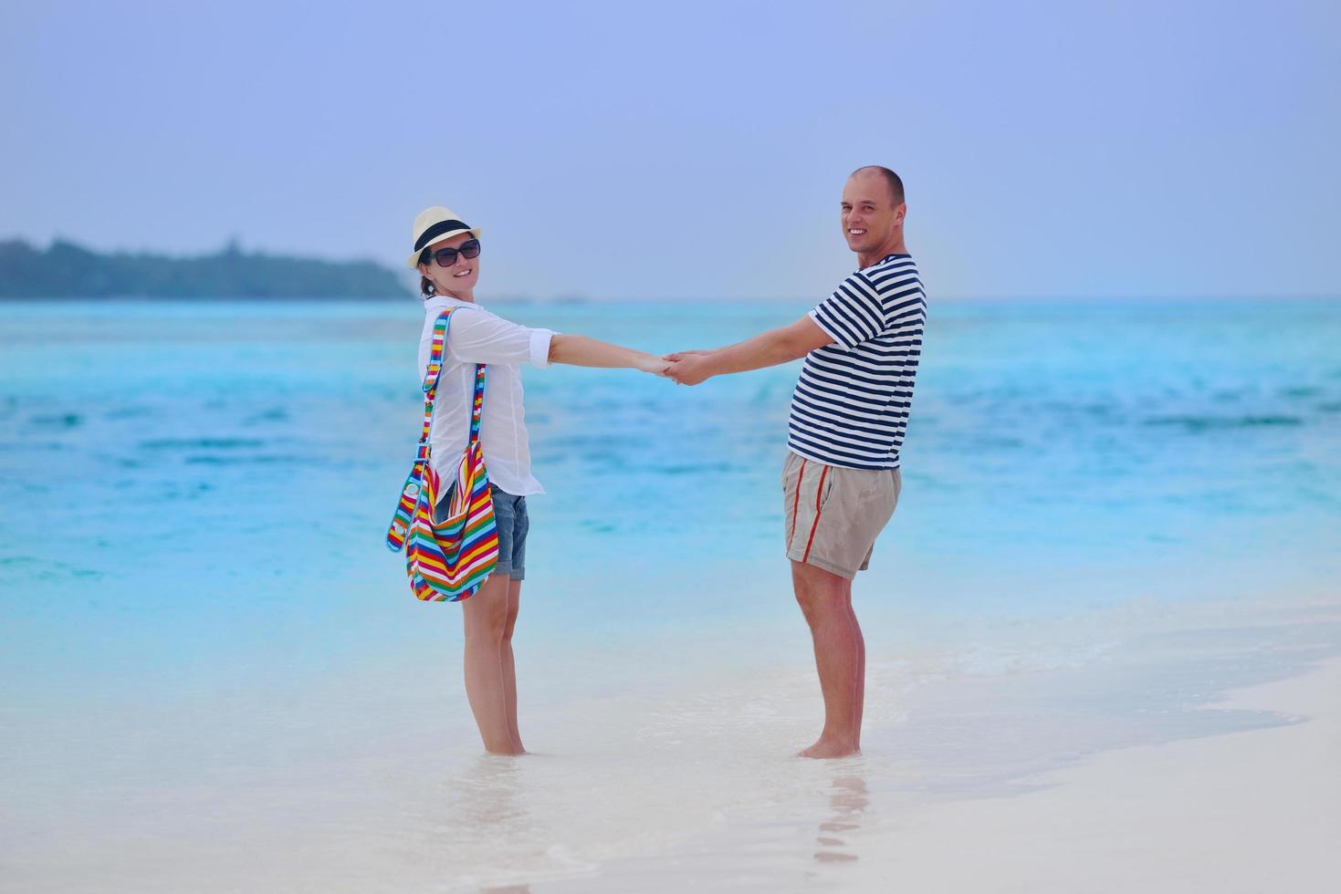 feliz pareja joven divertirse en la playa foto