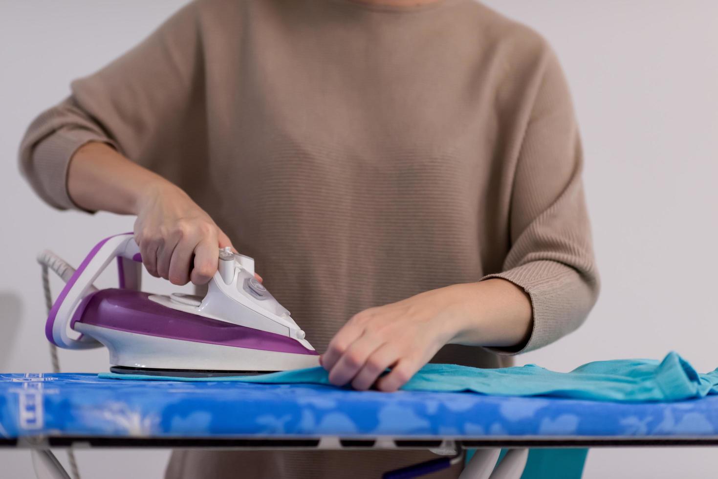 Red haired woman ironing clothes at home photo