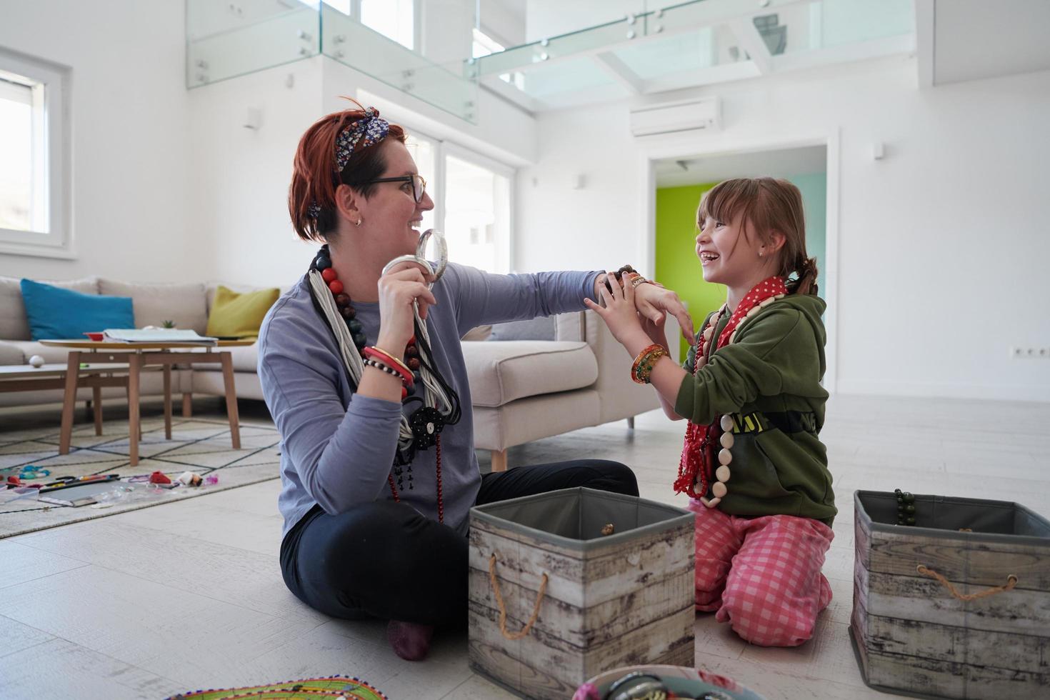 madre e hija pequeña jugando con joyas en casa foto
