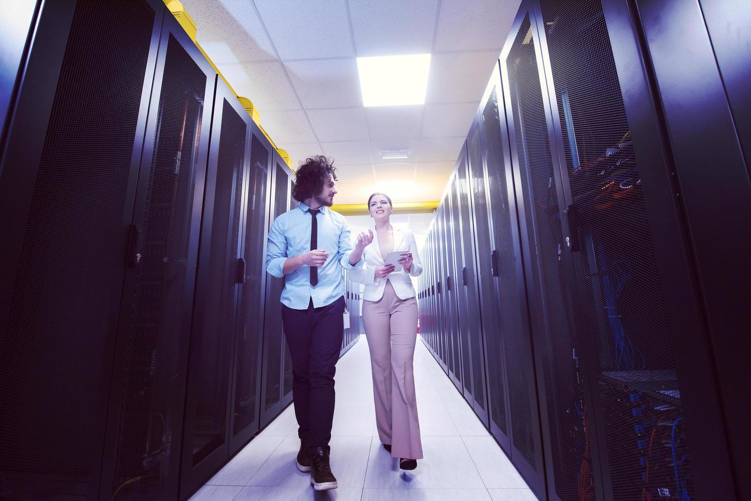 engineer showing working data center server room to female chief photo